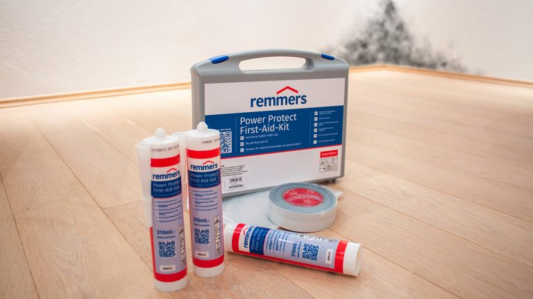 Remmers Power Protect First-Aid-Kid stehend auf Parkettboden, bestehend aus 3 Kartuschen, Klebeband, Schutzfolie und Aufkleber im praktischen Koffer