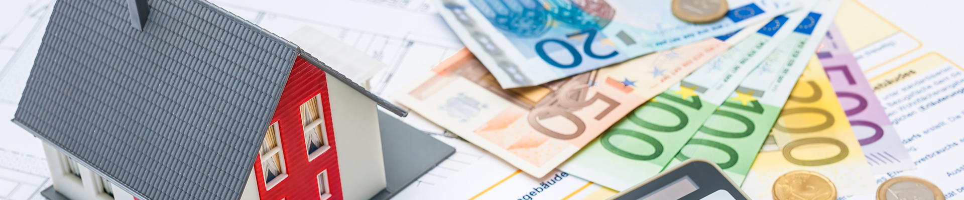 Modellaus, Taschenrechner, Geldscheine und -münzen liegend auf Bauplan