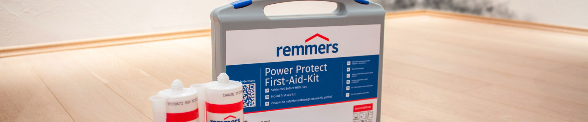 Remmers Power Protect First-Aid-Kid stehend auf Parkettboden, bestehend aus 3 Kartuschen, Klebeband, Schutzfolie und Aufkleber im praktischen Koffer
