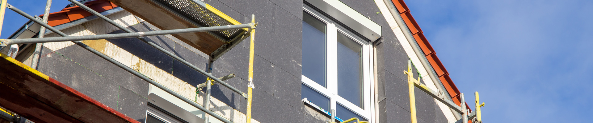 Fassade mit grauen Dämmplatten und Gerüst