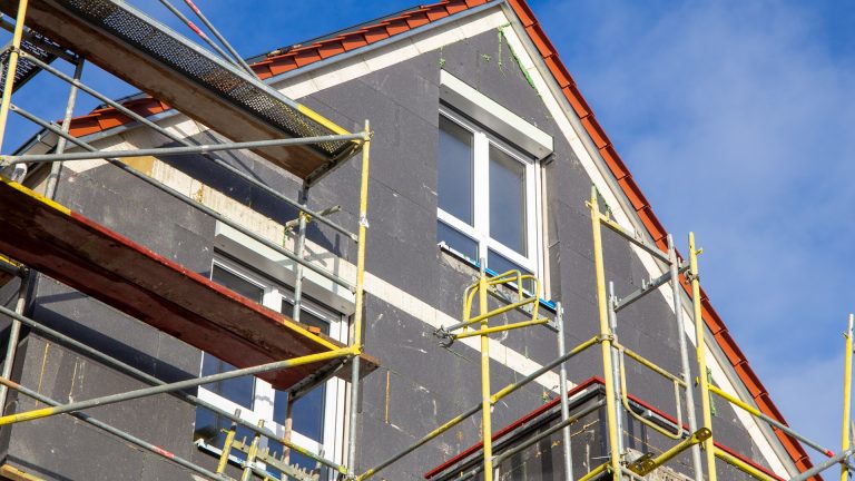 Fassade mit grauen Dämmplatten und Gerüst